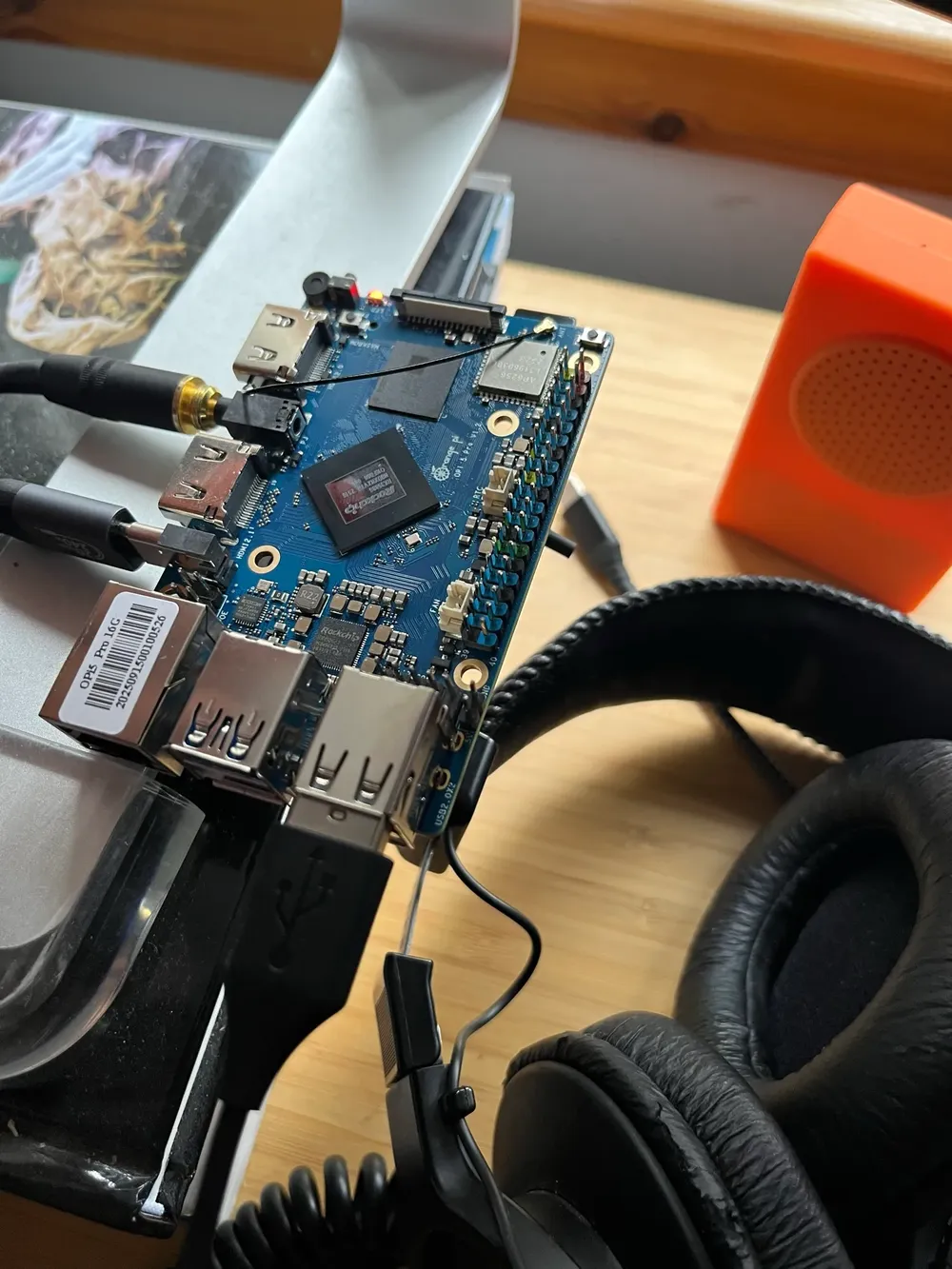 an orange pi plugged into various devices, some sony headphones and a buddha box in the background